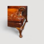 Pair of leather wing chairs with block and turned stretcher underframe